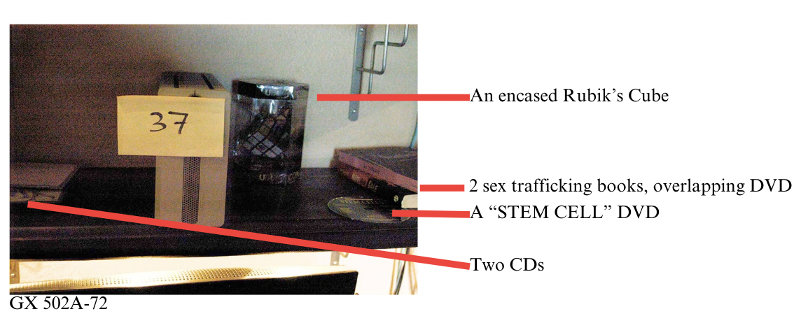 Annotated FBI search photo — Item 37 with each added prop (Rubik's Cube, Stem Cell DVD, two sex-trafficking books, CDs) labeled (IMAGE TO BE ADDED)