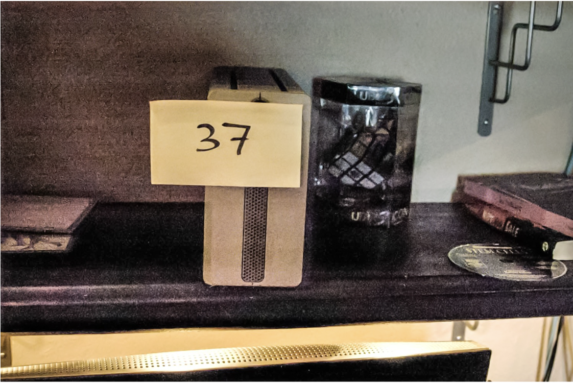 FBI search photo — bookshelf with Item 37, surrounded by added props (IMAGE TO BE ADDED)